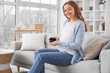 © Pixel-Shot - Young pregnant woman with dried prunes sitting on sofa at home