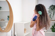 © Pixel-Shot - Beautiful young African-American woman with brush blow drying her healthy curly hair in bathroom