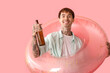 © Pixel-Shot - Tattooed young man with bottles of beer and inflatable ring on pink background
