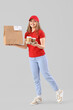 © Pixel-Shot - Female courier with food on grey background