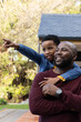 © wavebreak3 - African American father and son standing on deck in yard, father wearing watch, child pointing left