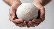 © MYKHAILO KUSHEI - Hands hold a cracked white sphere glowing softly during a creative art or design process in a studio setting