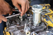 © Jumain - Close-up of a technician's hands using an L-key wrench to repair a heavy equipment hydraulic pump component in a mechanical workshop.