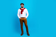 © deagreez - Confident young man in glasses and smart casual outfit posing against a bright blue background with a red sweater draped over his shoulders