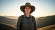 © deni - Woman hiker wearing a hat and backpack in the mountains at sunset.