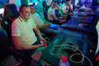 © .shock - Group Of Friends Gaming Together At A Neon-Lit LAN Party With Controllers And PCs