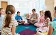 © .shock - Preschool teacher reading aloud to a group of children during circle time on a colorful rug