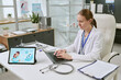 © AnnaStills - Young adult Caucasian female doctor typing on laptop in clinic, reviewing IVF information on tablet for fertility consultation