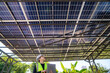 © ultramansk - Engineer inspecting solar panels under a solar-powered carport on a sunny day, ensuring optimal performance. Focus on renewable energy, sustainability, green power, and eco-friendly solar solutions.