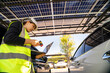 © ultramansk - Engineer in safety vest and helmet pointing towards a solar powered carport, illustrating eco-friendly innovation in parking infrastructure. Solar panels provide shade and sustainable energy.