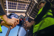© ultramansk - Engineer in safety vest and helmet pointing towards a solar powered carport, illustrating eco-friendly innovation in parking infrastructure. Solar panels provide shade and sustainable energy.