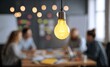 © Arifah - Bright Idea Light Bulb Illuminates Business Meeting Discussion.