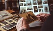 © Aulia - Elderly hands holding old photograph with laptop displaying vintage images.