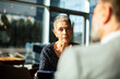 © Marko Geber - Senior businesswoman listening during meeting in modern office