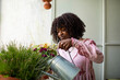 © Marko Geber - Woman watering potted plants on home balcony