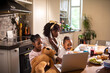 © Marko Geber - Mother multitasking with children at breakfast in home kitchen