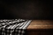 © AkuAku - Black and white checkered tablecloth on rustic wooden table with dark backdrop and copy space
