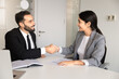 © fizkes - Two smiling multiethnic professional business partners shaking hands in corporate office, concluding agreement, expressing respect after productive collaboration. Teamwork, closing deal, partnership