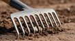 © Katerina Polibina - Metal garden rake resting on soil in outdoor setting