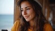 © Thares2020 - A young woman enjoys a moment of digital connection while relaxing on a sunny coastal patio overlooking the ocean