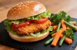 © FistaPrayudha - Close-up of crispy chicken burger with lettuce and tomato in sesame bun, served with fresh vegetables on dark slate, appetizing fast food meal