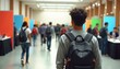 © miss irine - Young person with backpack walks in large hall. Many people attend job fair with colorful booths. Students seek career opportunities at university recruitment event.