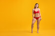 © New Africa - Beautiful woman in stylish swimsuit posing on yellow background. Space for text
