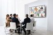 © New Africa - Team of office employees having video chat with remote coworkers in meeting room