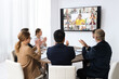 © New Africa - Team of office employees having video chat with remote coworkers in meeting room