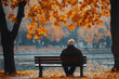 © Martinesku - Senior man sitting alone on park bench in autumn loneliness and retirement concept.