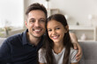 © fizkes - Close up portrait handsome dad posing seated on sofa with little daughter. Loving family posing for photo, capture cherished moment, enjoy good, friendly, warm relationships and quality time together