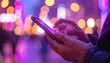 © MARYAM - Hands use a phone in a blurred city lights scape; shades of purple and orange bokeh