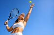 © iistais - Female tennis player serving ball from low angle against blue sky with copy space, power, fitness and outdoor sports concept