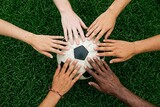 Six diverse hands of different skin tones touching soccer ball on green grass symbolizing unity and global connection