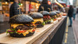© mh - Gourmet black beef burgers lined up on a wooden counter