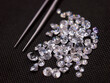 © .shock - Loose diamonds and gemstones with jeweler's tweezers on dark fabric background for luxury jewelry design