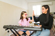 © AntonioDiaz - Music teacher and student giving high five during successful piano lesson, learning keyboard skills