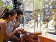© .shock - Couple window shopping for jewelry at a boutique display, smiling and pointing at rings and necklaces