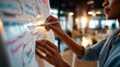 © Kateryna - Close up of hands at a bright office using a fishbone diagram on a whiteboard to root cause analyze a project issue with category branches labeled people process tools and