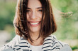 © deagreez - Smiling young woman portrait outdoors in natural light with short brown hair and striped sweater, happy casual lifestyle close-up showing bright smile and fresh spring atmosphere