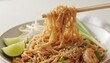 © Food stock - Delicious Pad Thai noodles with shrimp, peanuts, and lime being lifted by chopsticks