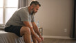 © Vyatcheslav - Thoughtful middle aged man sitting on the edge of a bed. Tired male with beard reflecting in bedroom. Morning routine or mental health concept