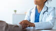 © Prostock-studio - A doctor meets with a patient at a medical office. The doctor has her hand on the patient's hand. They discuss health concerns. The setting is bright and has a neutral design.