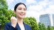 © YT - 高層ビルと青空を背景に未来を見つめながらガッツポーズをする女性ビジネスパーソン、昇進や成長、企業ブランディングに適した前向きな広告向け人物ビジュアル