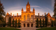 © rasdiana - Majestic architecture of a historic university building featuring a clock tower under a warm sunset glow and orange sky
