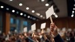 © Fluffik - People hold blank signs during a public event in a large indoor space in the evening with many attendees around them