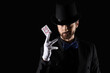 © Pixel-Shot - Male magician with playing card on black background