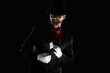 © Pixel-Shot - Male magician taking playing card from his jacket on black background