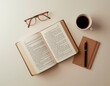 © Ольга - Top view flat lay of an open book, coffee cup, reading glasses, pen and notebook arranged on a clean light background, cozy minimal composition, warm tones