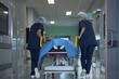 © DragonImages - Medical team transporting patient on hospital gurney through corridor, preparing for surgery or emergency care. Useful for healthcare services, hospital workflow, urgent treatment campaigns